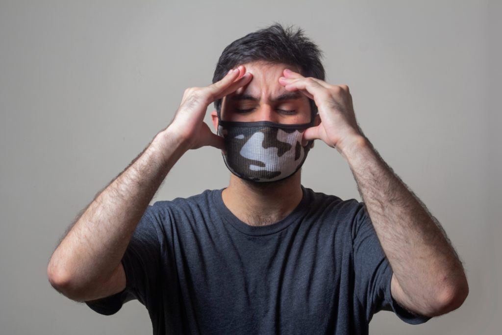 A man wearing a face mask looking stressed